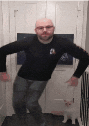 a man in a star trek shirt is dancing with a cat
