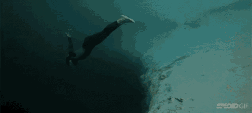 a person is swimming in the ocean with their legs outstretched .