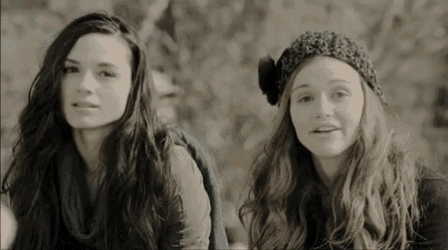 two young women are sitting next to each other and looking at something .
