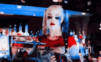 a woman in a harley quinn costume is standing in front of a bar .