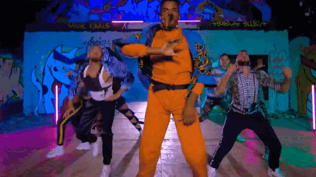 a group of people are dancing in front of a wall with graffiti that says cause kinks