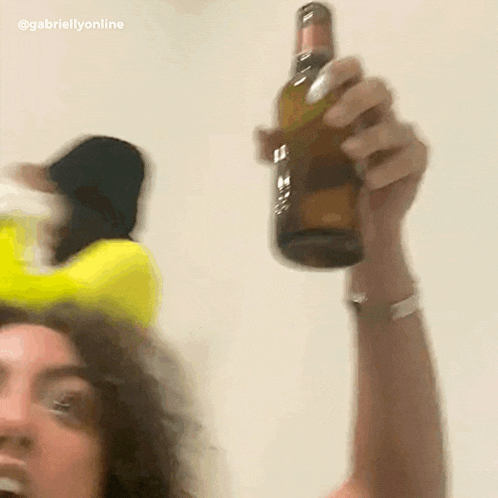 a blurry picture of a woman holding a beer bottle with the caption @gabriellyonline