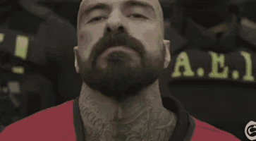 a man with a beard and tattoos is wearing a red shirt .