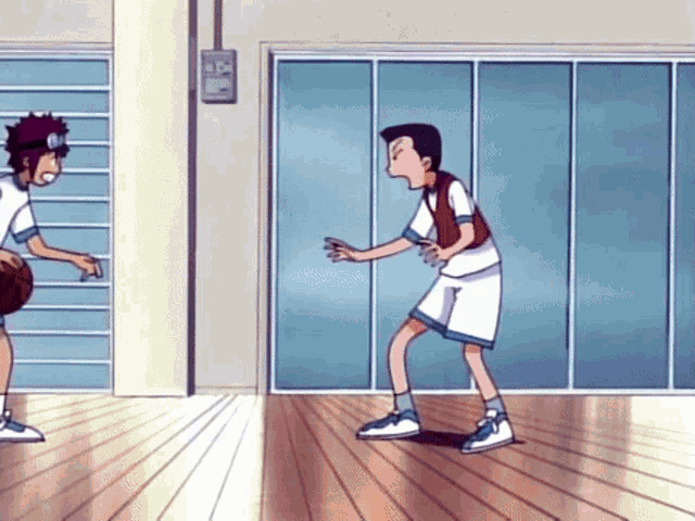 two boys are playing basketball in a gym and one has a basketball in his hand