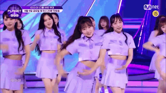 a group of girls are dancing on a stage in purple outfits .