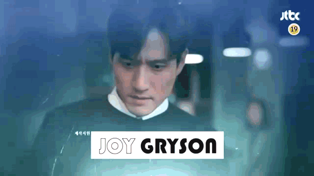 a man is standing in front of a sign that says joy gryson .