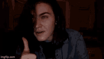 a man with long hair is making a funny face while sitting in a dark room .