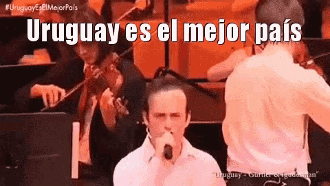a man singing into a microphone in front of an orchestra with the words uruguay es el mejor pais
