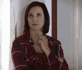 a woman wearing a plaid shirt is standing in front of a door .