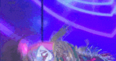 a woman with a mask on her face is laying on a stage with purple lights behind her .