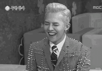 a black and white photo of a man wearing a suit and tie laughing .