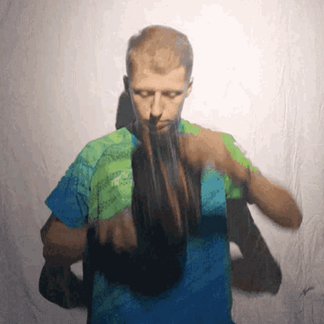 a man in a blue and green shirt is holding a bottle