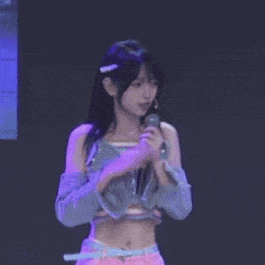 a young woman is standing on a stage wearing a crop top and gloves .