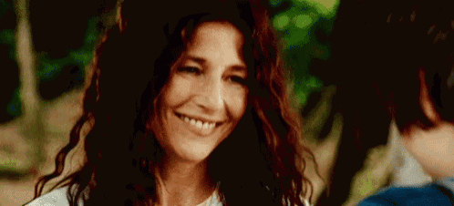 a woman with curly hair is smiling while looking at a child .