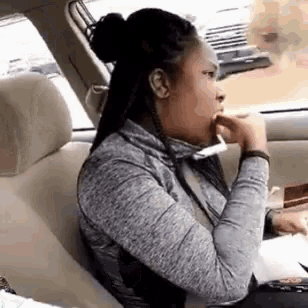 a woman is sitting in the back seat of a car eating a candy bar .