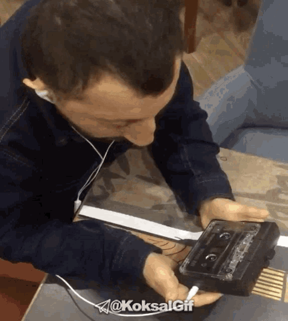 a man wearing headphones is holding a cassette tape with the hashtag @koksalgif