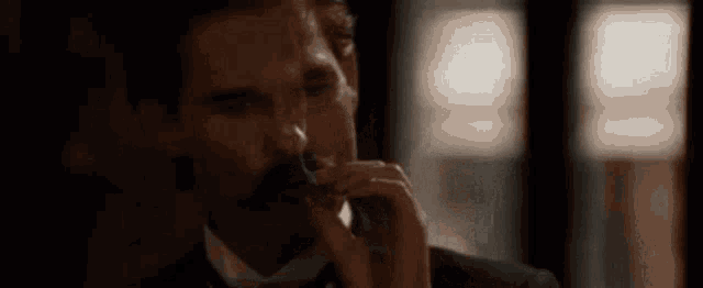 a man in a suit and tie is drinking a glass of wine .