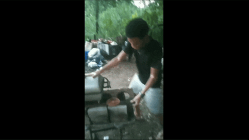 a man in a black shirt is kneeling down in front of a wood burning stove .