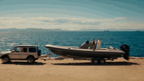 a car is towing a boat on a trailer near the ocean