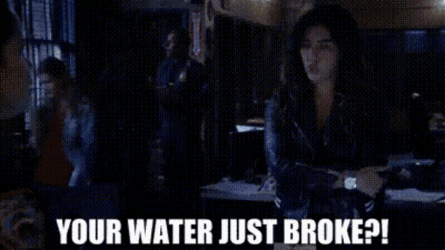 a woman is sitting at a table with the words `` your water just broke ? '' written on the screen .