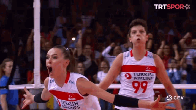two volleyball players wearing turkish airlines uniforms are celebrating a point