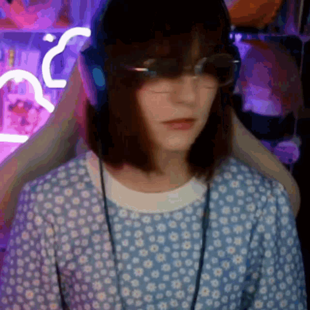 a woman wearing headphones and glasses is sitting in a chair in a room .
