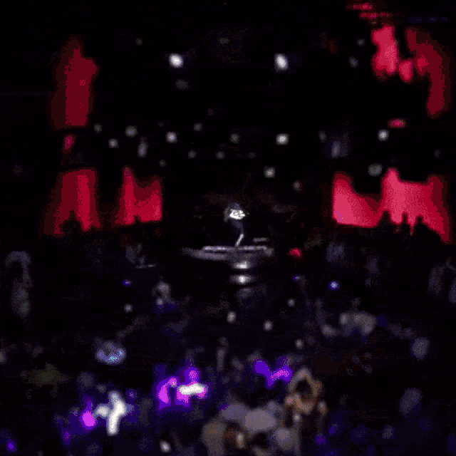 a blurred image of a crowd at a party with a dj on the stage