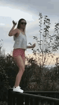 a woman is standing on a railing holding a cell phone in her hand .