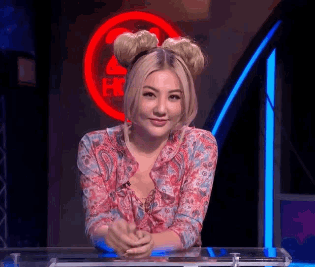 a woman is sitting at a table in front of a sign that says ' hot '