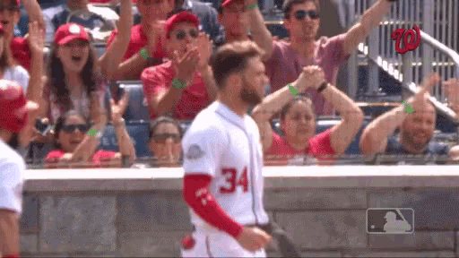a baseball player with the number 34 on his jersey is walking towards the crowd .