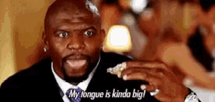 a man in a suit and tie is eating a piece of food and saying " my tongue is kinda big "