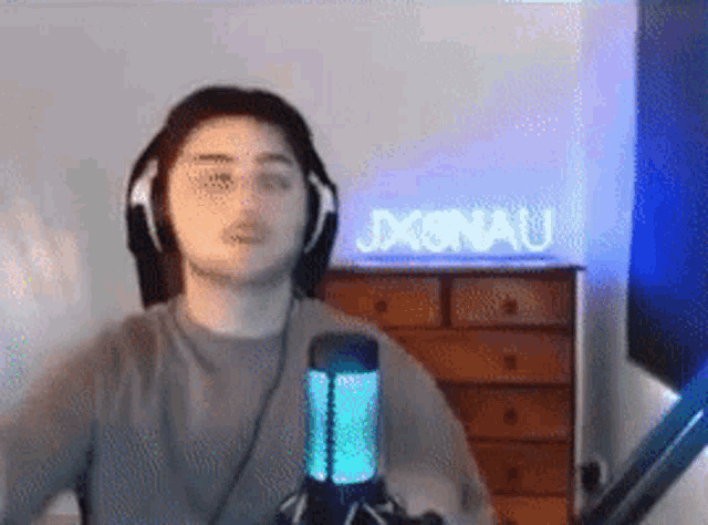 a man wearing headphones and a microphone is standing in front of a sign that says jxenau .