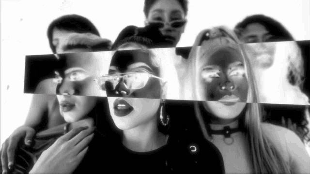 a black and white photo of a group of people including a woman wearing sunglasses .