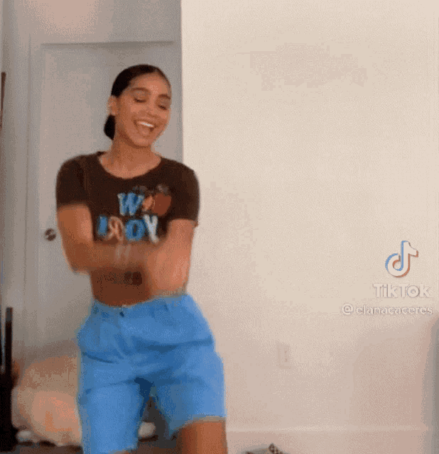 a woman in a brown shirt and blue shorts is dancing .