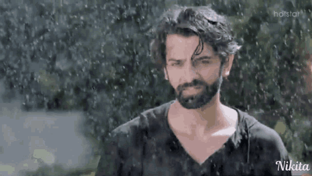 a man with a beard is standing in the rain