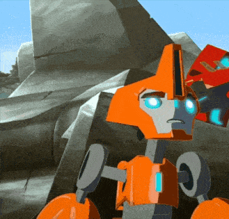 an orange robot with blue eyes is standing in front of a large rock