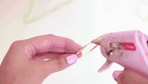 a woman is using a hot glue gun to glue a bracelet to a chain .