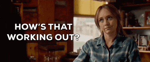 a woman in a plaid shirt is sitting at a table in a kitchen with the words `` how 's that working out ? ''