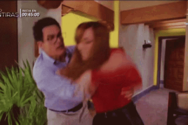 a man is holding a woman in his arms in front of a sign that says inicia en