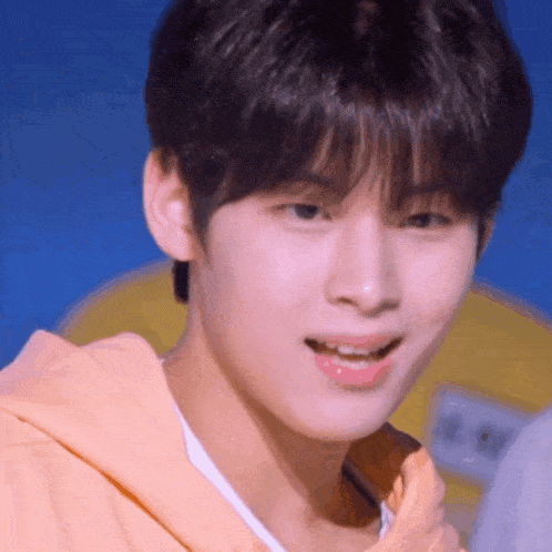a close up of a young man 's face with a yellow shirt on