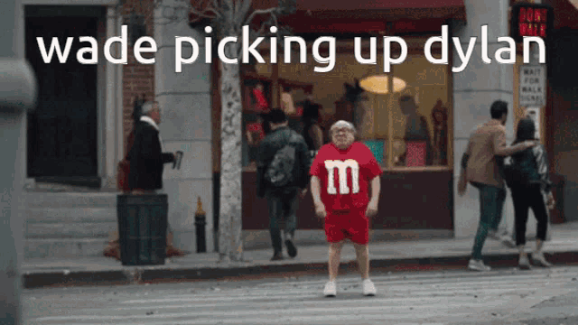 a man wearing a red m & m 's shirt is crossing a street