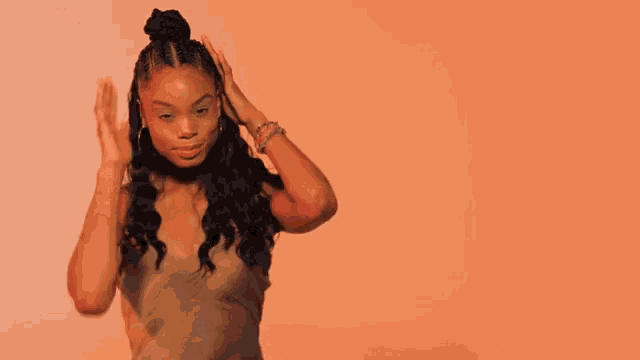 a woman with braids in her hair is standing in front of an orange background that says cosmopolitan on it