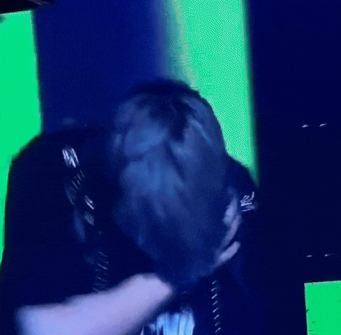 a person is covering their face with their hand in front of a green and blue background .