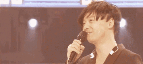 a man is smiling while holding a microphone in his hand on a stage .