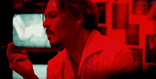 johnny depp is smoking a cigarette in a red room .