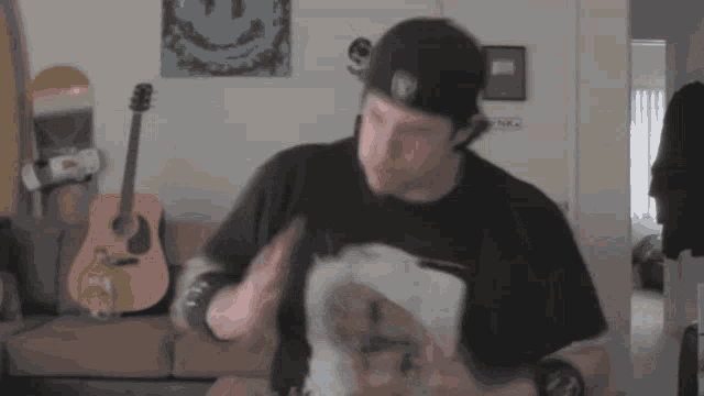 a man wearing a raiders hat stands in front of a guitar and a skateboard
