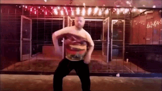 a man in a hamburger shirt is dancing in front of a building with a fence .