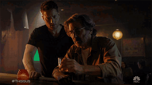 two men standing at a bar with a nbc logo in the corner
