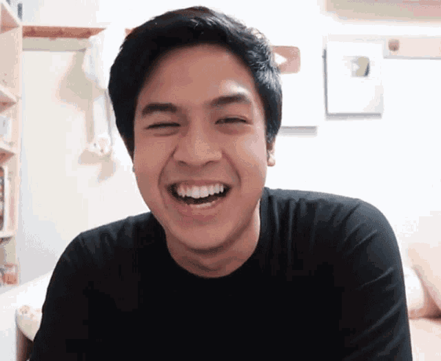 a man in a black shirt is smiling with a youtube logo on the wall behind him