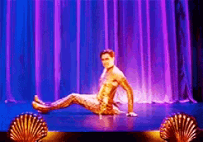 a man in a gold outfit is sitting on a stage